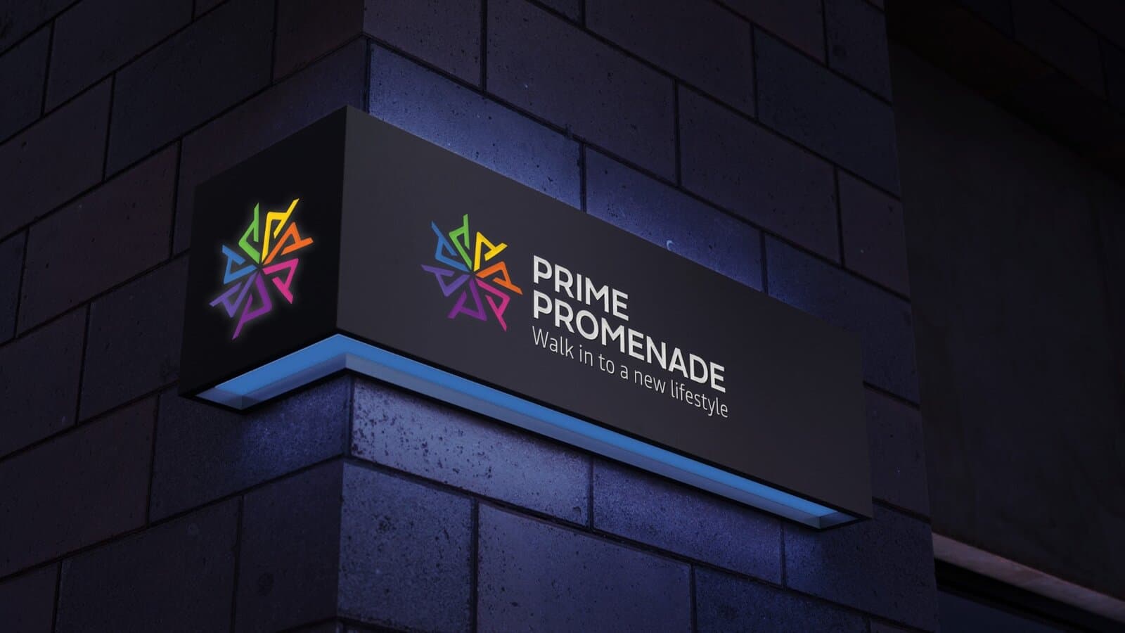 An illuminated Prime Promenade sign mounted on a building corner at night, lit from below